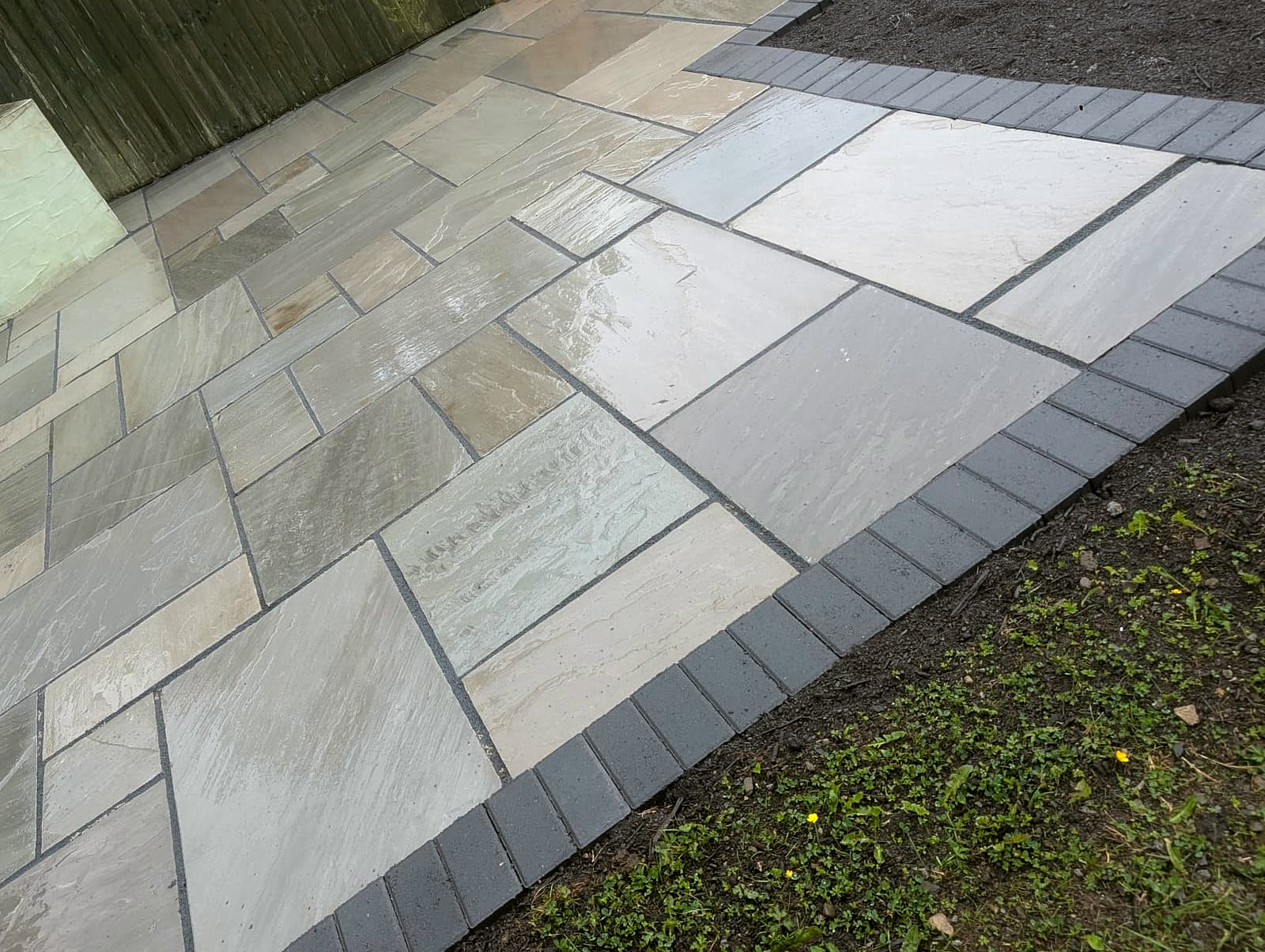 Grey Indian sandstone patio with a dark block-paving border