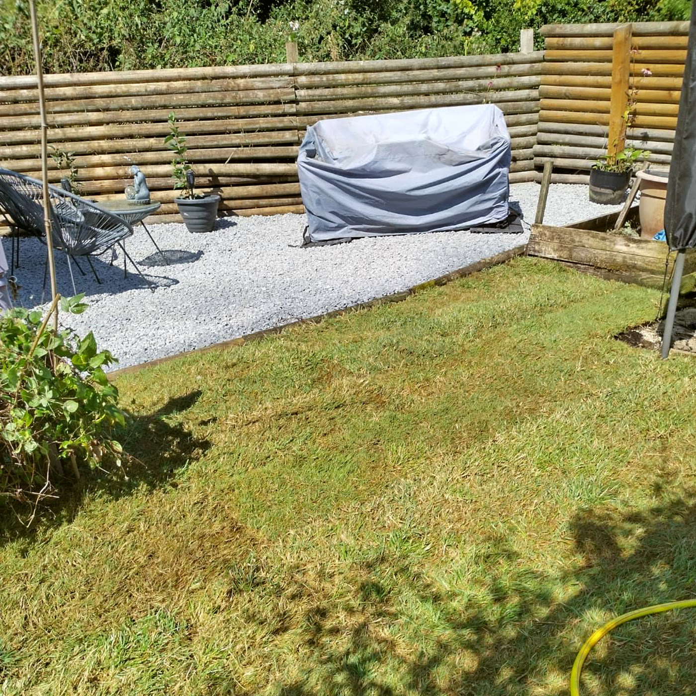 A cleared garden with new turf and a gravel seating area